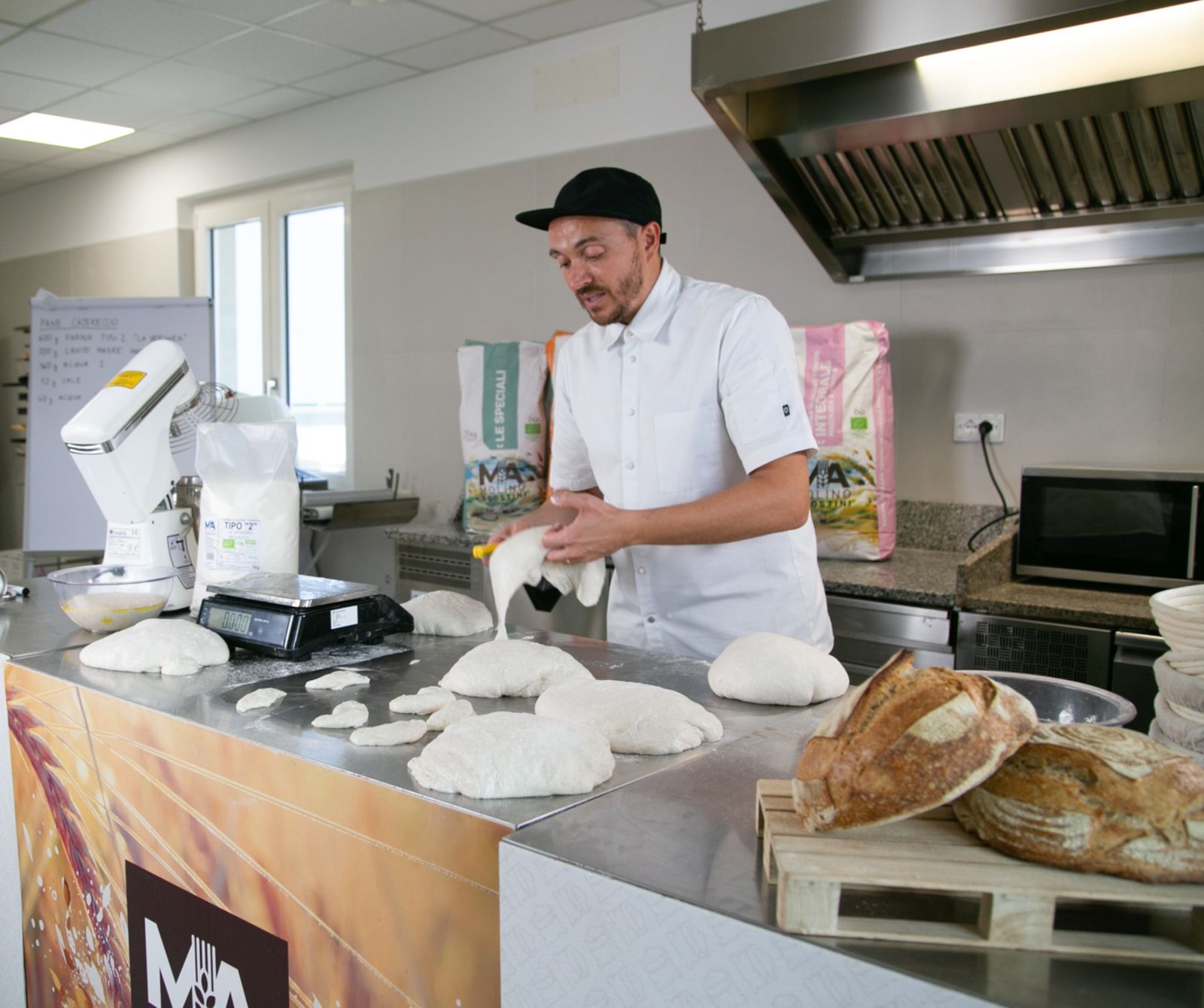 Panificatore al lavoro in un laboratorio con pane appena sfornato
